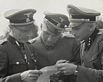 Richard Baer and Karl Höcker look over a document with SS-Standartenführer Dr. Enno Lolling, the director of the Office for Sanitation and Hygiene in the Inspectorate of Concentration Camps. From left to right: Lolling, Baer, Höcker.
