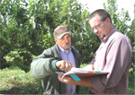 amid the cherry tree branches of one of G&G’s orchards, Rene Garcia (left) and NRCS Conservation Agronomist Kevin Davis review the Garcia’s CSP conservation plan (NRCS photo)