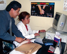In Bolivia, Dr. Percy Calderon (left), assists a health worker in analyzing HIV/AIDS trends using a new, PEPFAR-supported automated reporting system.