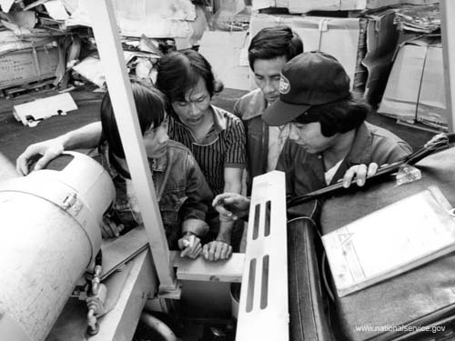 VISTA member Do Hiew (right) teaches Vietnamese refugees forklift maintenance in San Francisco. He began his VISTA assignment with Project Achieve in May 1980 as a recruiter and outreach worker. Hiew, 30, came to the United States in October 1979. He has a degree in economics.