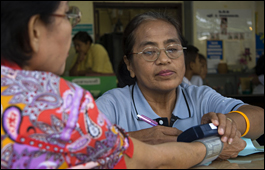 A health worker examining a woman's blood pressure at a primary health care centre in Thailand.
