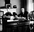 Theodore Roosevelt sitting at his desk