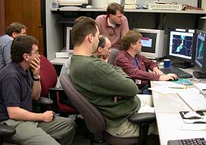 Members of a forecast team evaluate model output on computer monitors