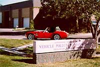 Photo of red sports car parked in front of Vehicle Pollution Management Division building.