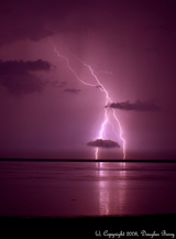 forked lightning in pink sky with clouds over water