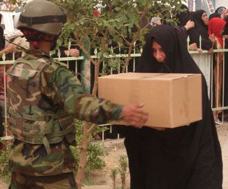 A local Iraqi woman receives a humanitarian assistance package from an Iraqi Army Soldier in the Shulla community in northwest Baghdad, Sept. 10, 2008.  Photo by 1st Lt. Christopher Taylor, 2nd Brigade Combat Team, 101st Airborne Division (AA) Public Affairs.