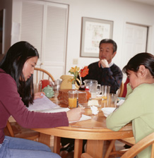 girl studying at table with parents