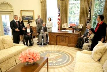 Photo of President George W. Bush and former President George H. W. Bush visiting with Access Board Chair Jan Tuck, Chair of the National Council on Disability Lex Frieden, and others in the Oval Office after the signing of the Presidential Proclamation to Commemorate the 15th Anniversary of the Americans with Disabilities Act in the Oval Office on July 26th. Tuck and Frieden appear to the right of the President.