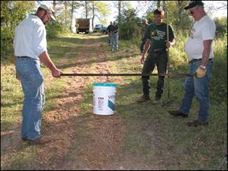 Figure 10—Application of Vitri-Turf to bridle trail by drip-bucket method. Holes drilled in bottom of 19-L (5-gal) container allowed uniform application over 0.4- by 20-m (1.3- by 66-ft) trail.