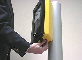 Figure 3.  Photo.  Pedestrian Signal Call Device used at Puffin Crossings.  This photo illustrates a man holding the bottom of a Puffin signal box.  A virbro-tactile knob let’s users know when the crossing phase has begun.