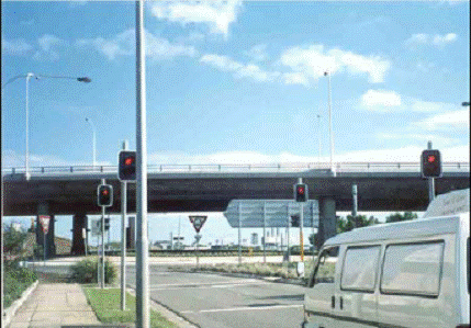 Figure 6.  Photo.  Signalized roundabout crosswalk in Sydney, Australia.  This photograph shows an approach to a roundabout in Australia.  Two pairs of signals have been installed on the approach on both side of the roadway: the first pair is about 40 feet from the crosswalk; the second pair is adjacent to the crosswalk.