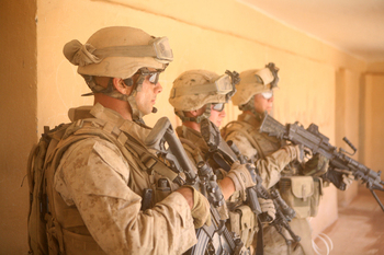 Marine scouts prepare to search an old Iraqi school during a patrol through Um Al Wazz, Iraq, on Aug. 2. Marines visited the towns of Um Al Wazz and Midham to search the area and question the citizens about suspicious activity and knowledge of oil smuggling that funds and supports the insurgency.