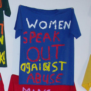 photo of 15 hand made t-shirts, focusing on one reading 'women speak out against abuse'