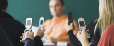 Foto: estudiantes que leen mensajes de texto en sus teléfonos celulares.