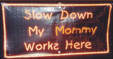 This shows a highway sign that reads:  Slow Down My Mommy Works Here