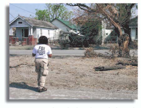 Photograph of a member of the F B I's Evidence Response Team photographs damage caused by Hurricane Katrina in New Orleans