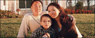 Photo: A family in sitting in front of their house.