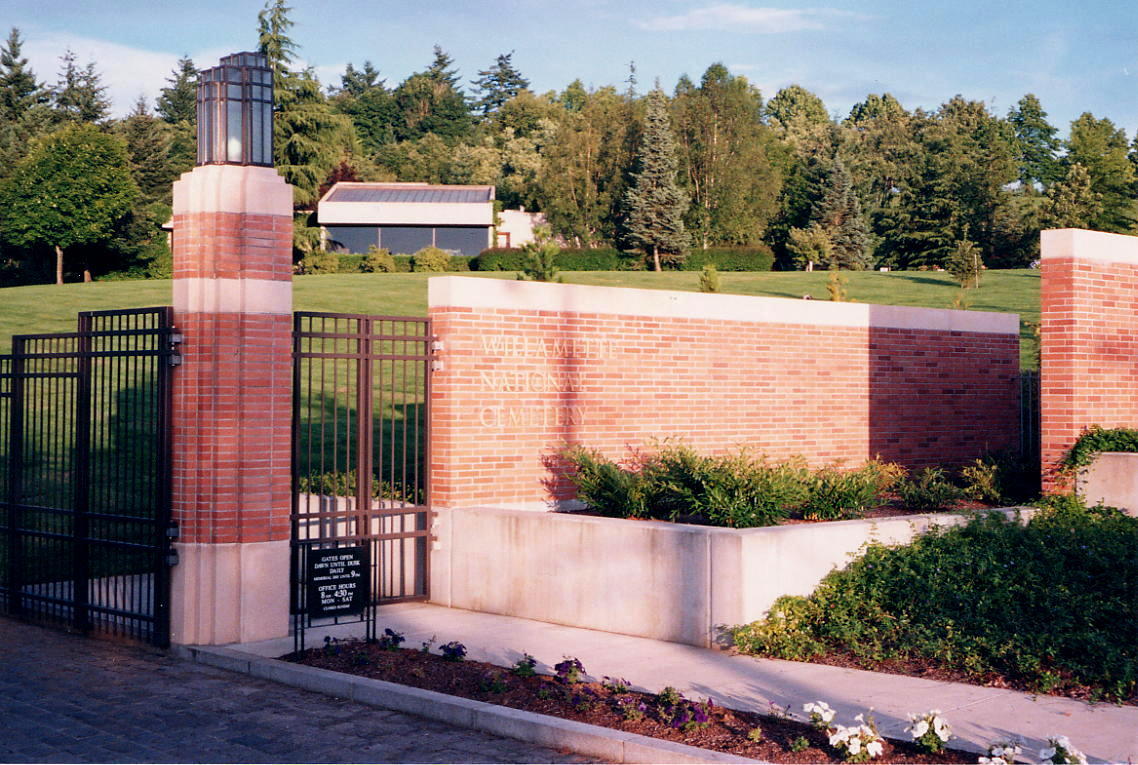 A photo of a brick entrance gate with Willamette's administration building and trees viewed in the background.