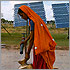 Thumbnail photo of a woman filling a gourd with water at a pump that is in front of a PV module.
