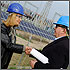 Photo of a man and a woman shaking hands in front of a photovoltaic (PV) array.