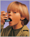a photo of a young boy using an inhaler