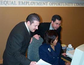 Photo of three people looking at a computer monitor