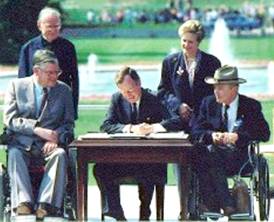 President George H.W. Bush signs the ADA into law in the presence of  Evan Kemp, Chairman, Equal Employment Opportunity Commission, Justin Dart, Chairman, President's Committee on Employment of People with Disabilities, the Rev. Harold Wilke, and Sandra Swift Parrino, Chairperson, National Council on Disability.