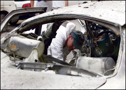 An FBI agent collects evidence from an exploded car in Lebanon. AP Photo.