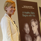 Campaign spokesperson Tonya Lewis Lee standing next to A Healthy Baby Begins with You poster