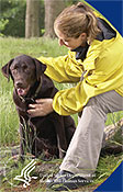 A woman petting her black lab.