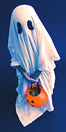 A child dressed as a ghost carrying a plastic pumpkin full of candy.