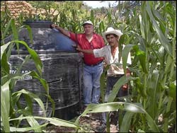 Photo: José Pérez (right) shows visitors the water storage tank he installed on his farm.
