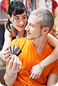 A man holding 3 credit cards; a woman behind him trying to take the credit cards.