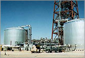 A photo of two, gray, thermal energy storage system tanks, which are very large, at a parabolic trough power plant.