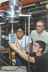 A researcher instructs two students in X-ray scattering.