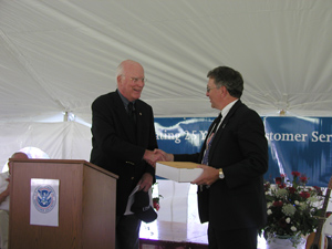 Vermont Senator Patrick Leahy presents Paul Novak, Director of the Vermont Service Center, with a flag flown over the U.S. Capitol to commemorate the 25th anniversary of the USCIS Service Centers.