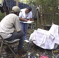 Team member Peggy O'Neal interviews a homeless man in a wooded area.