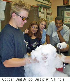 Foto de um estudante segurando uma proveta de laboratório com gelo seco (dióxido de carbono congelado) nele- a névoa é um exemplo de sublimação. 