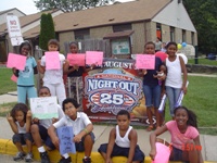 [Photo: Youth from Garrison Woods Neighborhood Networks Computer Training Center pose with the National Night Out banner.]