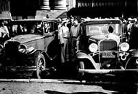 This is a photograph of people looking at destroyed cars from the Kansas City Massacre