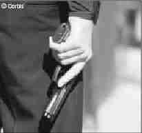 Photograph of a police officer holding his drawn weapon at his side