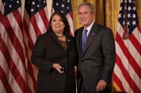 President George W. Bush presented the President’s Volunteer Service Award to Marie Arcos, of Houston, Texas in a ceremony in the East Room of the White House on October 7, 2005.  The ceremony, part of a White House celebration of Hispanic Heritage Month, was also attended by Attorney General Alberto Gonzales and Secretary of Commerce Carlos Gutierrez.