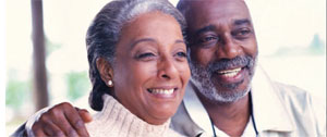 An older man and woman standing close together, smiling.