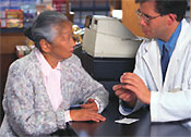 A pharmacist explaining a medication to an older woman.