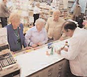 A pharmacy counter; the pharmacist is helping 2 older women and 1 older man.