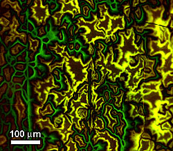 Magneto-optical image of magnetic fields within a YBCO superconductor showing electrically connected grains (yellow) and grain boundaries (green) that form barriers to superconducting currents