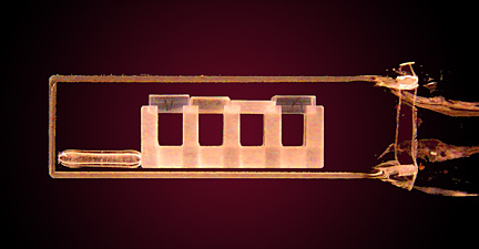 apparatus holding four small squares of glass inside a vaccuum chamber