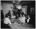  Orville Wright and group around a table, looking at photographs, during a party at 7 Hawthorn Street