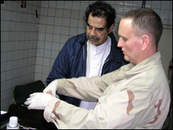 Image of Saddam Hussein being fingerprinted by an FBI agent