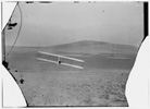  Rear view of Wilbur making a right turn in glide from No. 2 Hill, right wing tipped close to the ground. 
